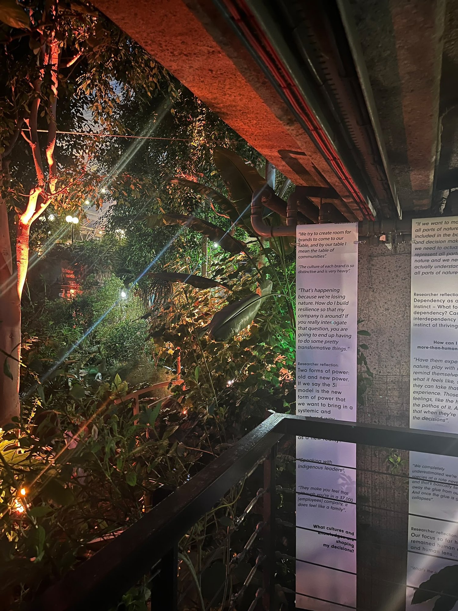 Long printed banners of quotes and researcher reflections hanging beside the Conservatory greenery