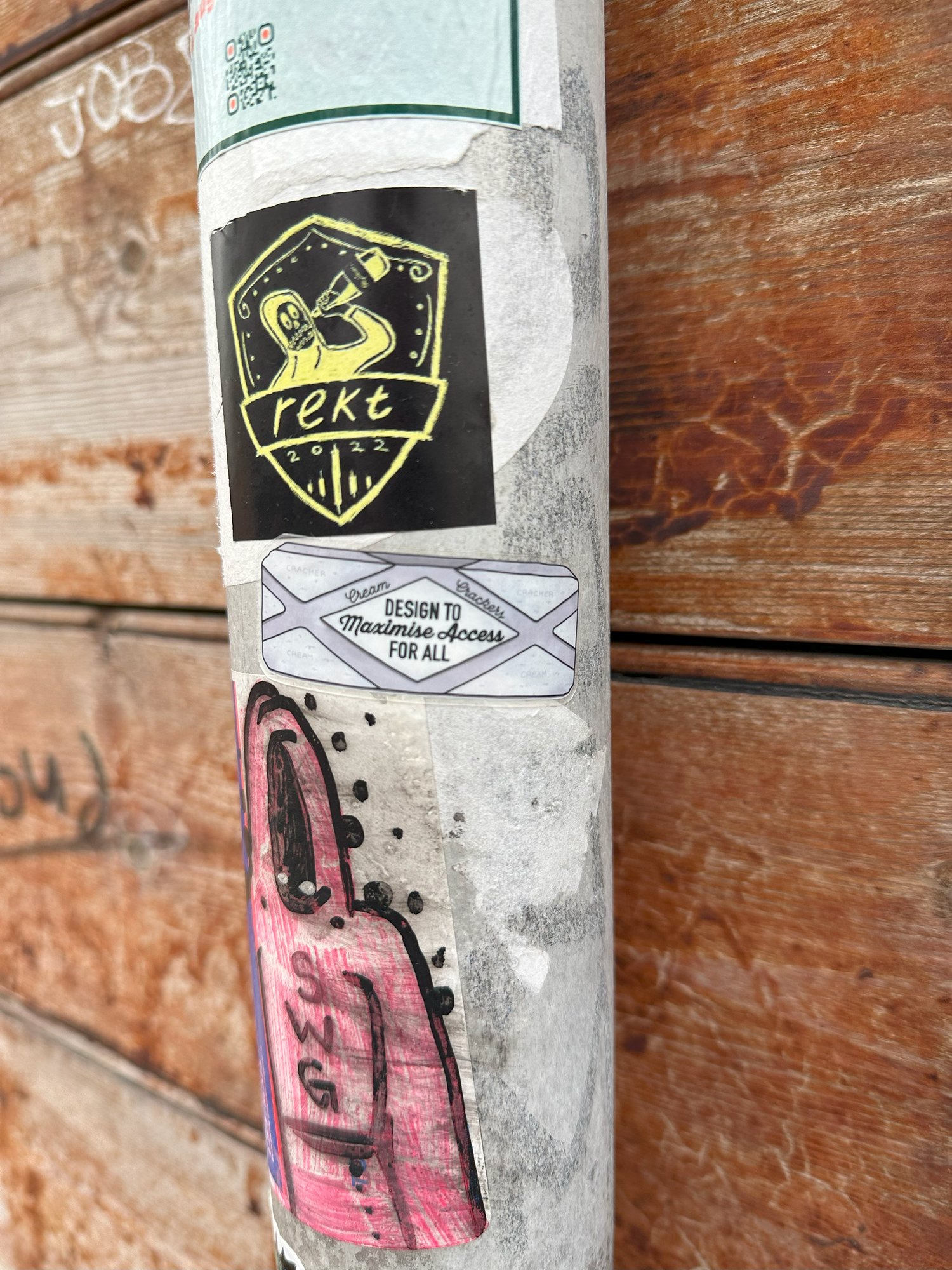 A heuristic sticker on a lamppost among other street stickers