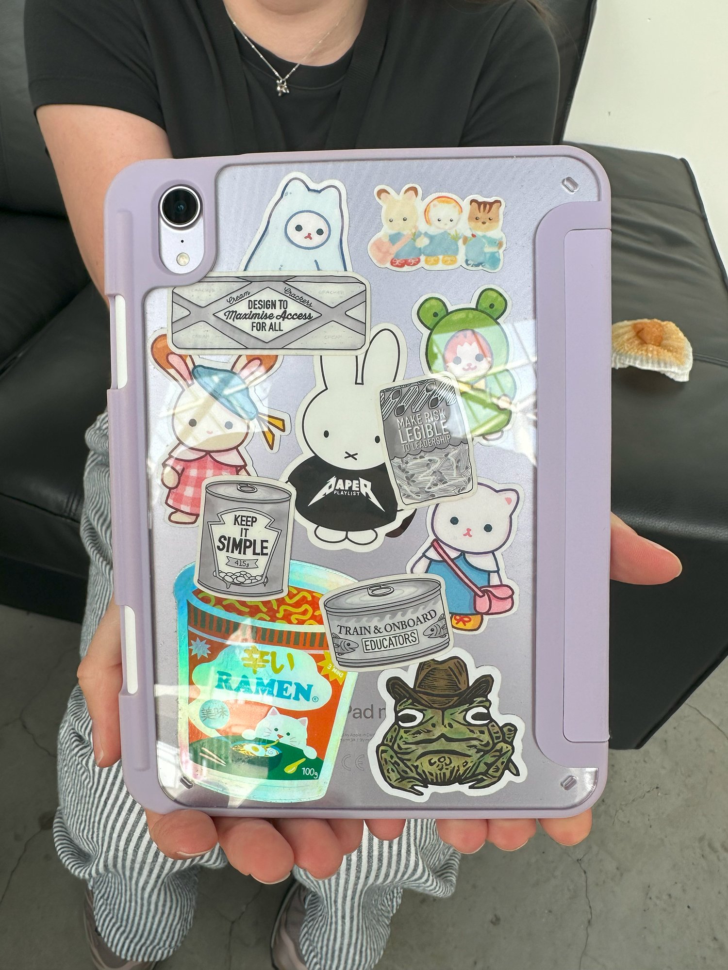 Someone holding a tablet case decorated with heuristic and other stickers
