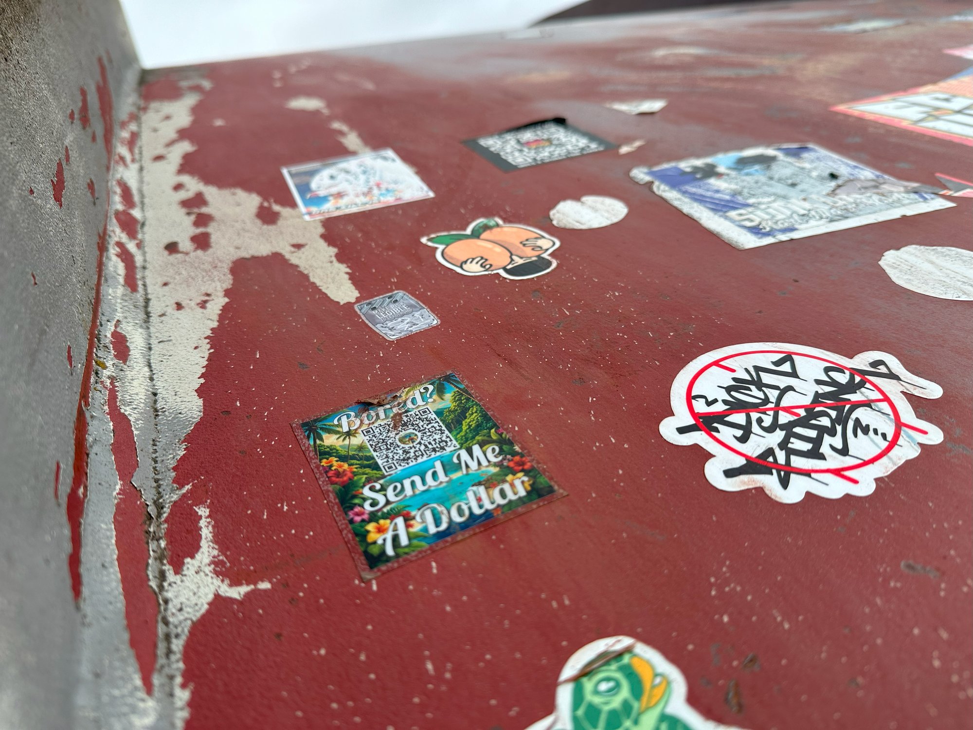 Heuristic stickers mixed in with others on a weathered red surface
